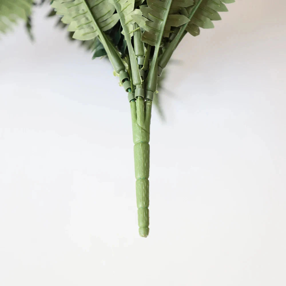 two faux boston fern plants placed on tall bookshelf with fronds cascading over edges adding greenery to home library