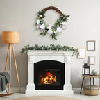 white rose wreath hanging on dark wood front door with brass knocker welcoming guests for spring season