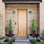 set of 2 elegant spiral topiary trees on covered porch steps for refined traditional style entry