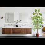 tall artificial olive tree standing in two-story foyer entrance next to staircase demonstrating grand scale